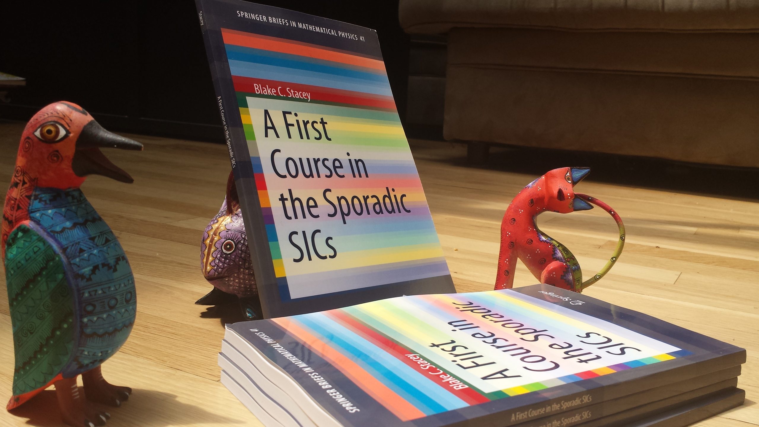 Copies of a textbook surrounded by Oaxacan carved wooden animals